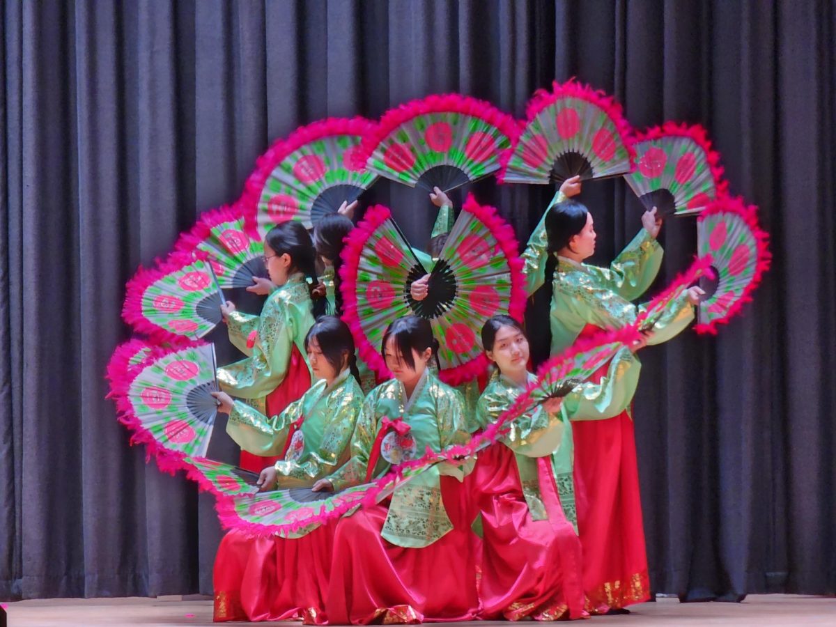 Korean language students performing Buchaechum using fans, which represents the variety of nature. The formations of this dance depict images of nature, including birds, flowers, dragons, and waves. 