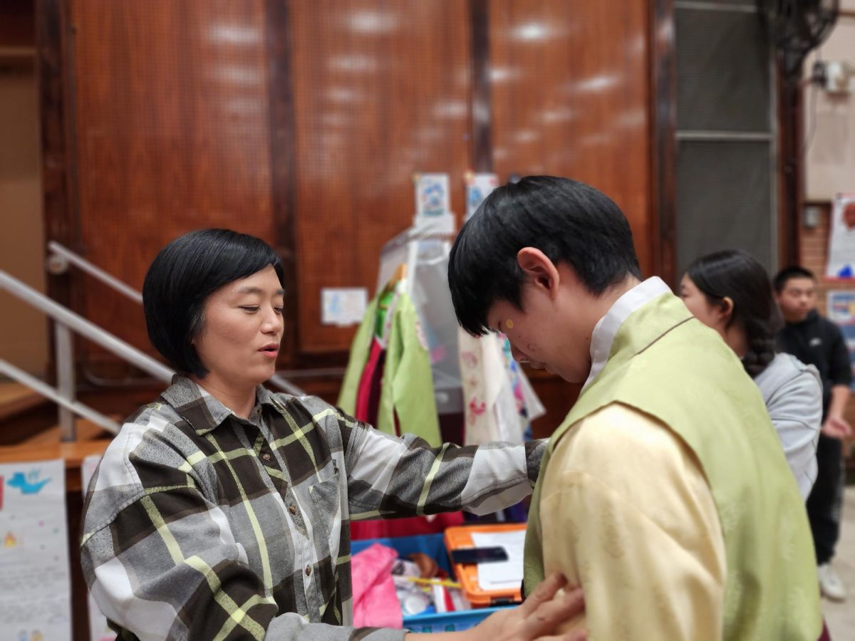 Korean language teacher, Ms. Kwon, helping a student wearing a hanbok.
