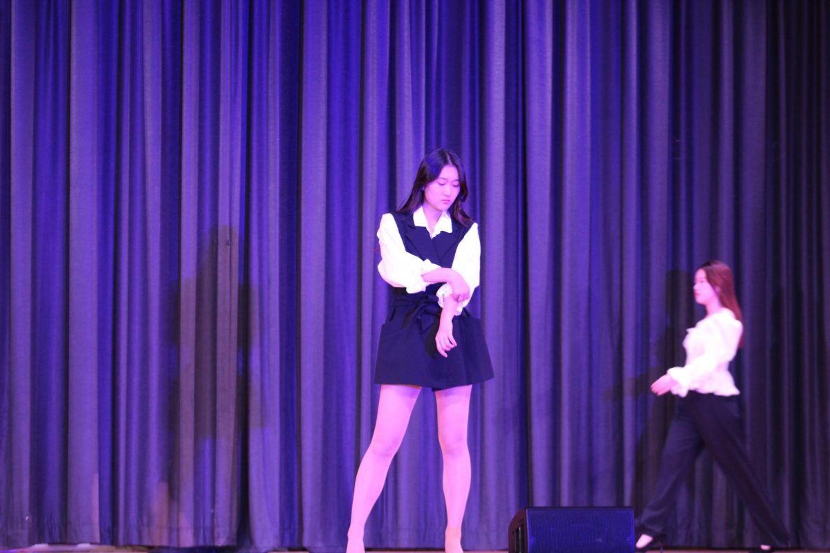 Hannah Kim (center) showcases her business-style dress as Jingyi Lin (right) walks out. Their outfits match in black and white with ruffled sleeves. 