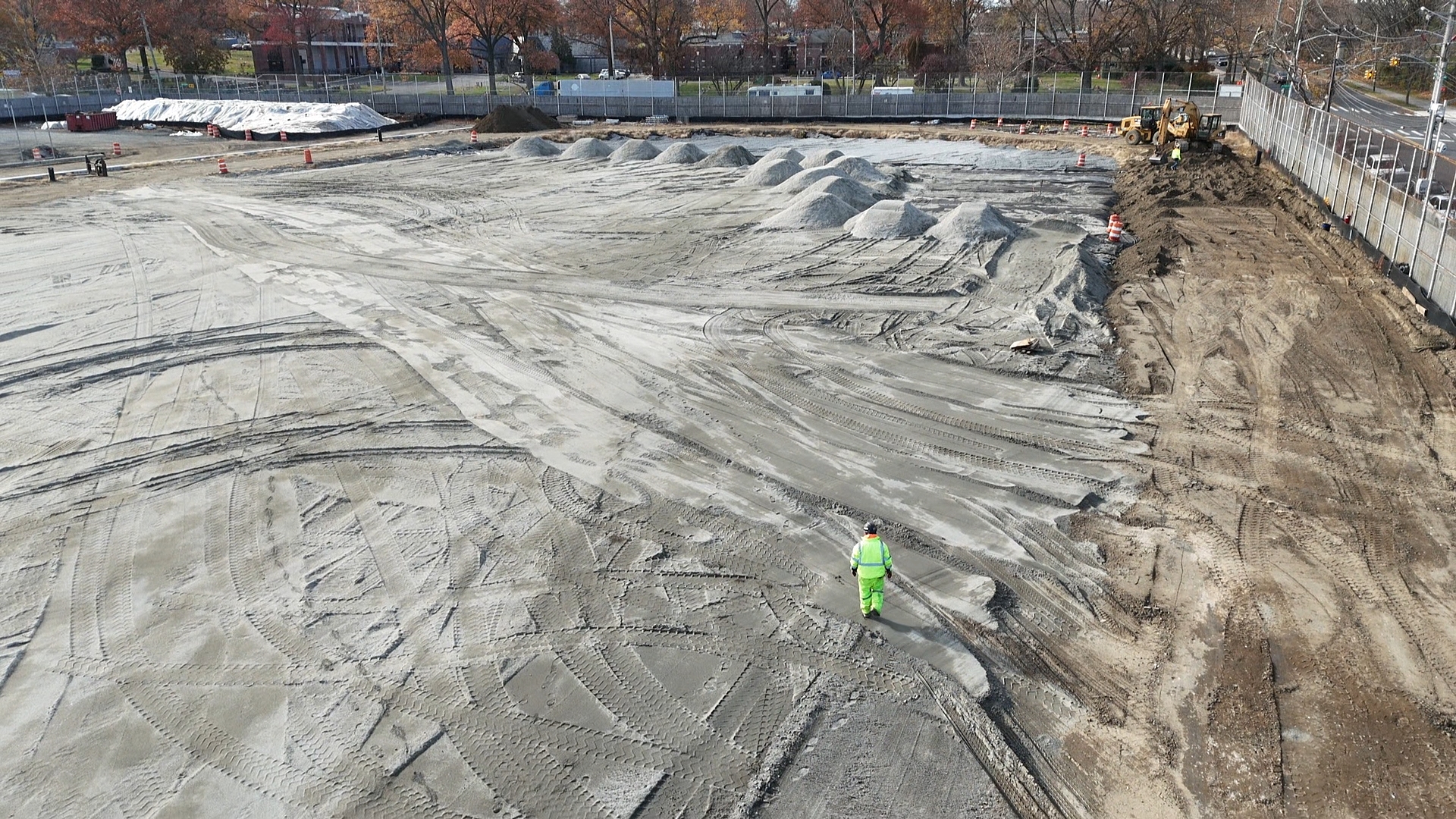 A drone image shows a single construction worker on the Francis Lewis High School field.